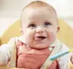 Bebé con una cuchara en la mano sonriendo