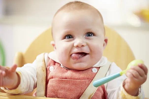 Bebé con una cuchara en la mano sonriendo