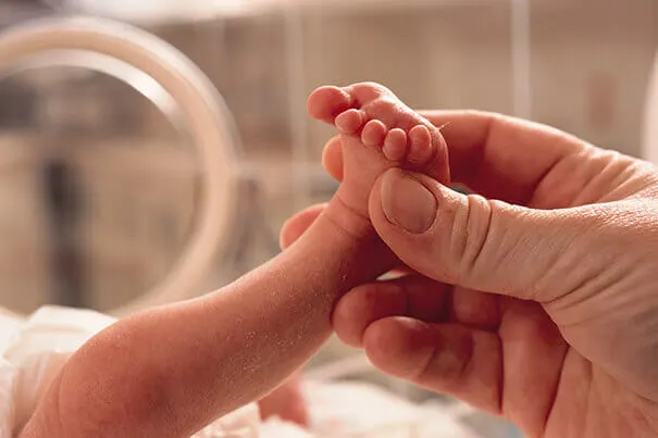 Mano tocando el pie de un bebé recien nacido