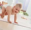 Bebé en pañales aprendiendo a caminar