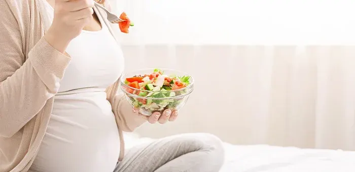 Mujer embarazada consumiendo vegetales verdes para obtener calcio