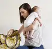 Mujer alzando a su bebé mientras busca en su pañalera