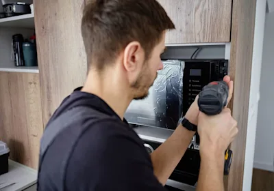 technician-fitting-microwave-with-drill