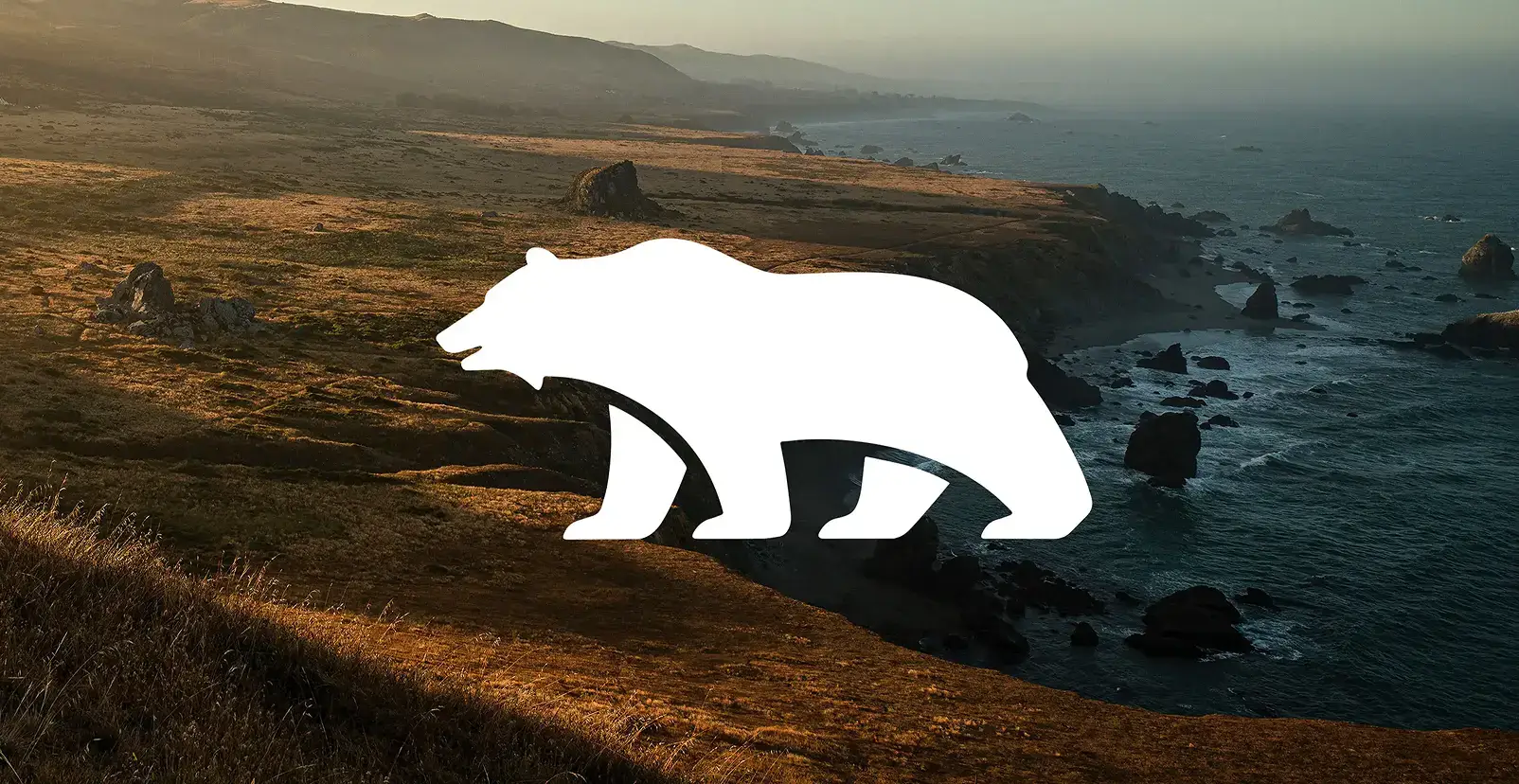 White bear silhouette overlaid on a scenic California coastline with golden cliffs, rocky shores, and blue ocean waters.