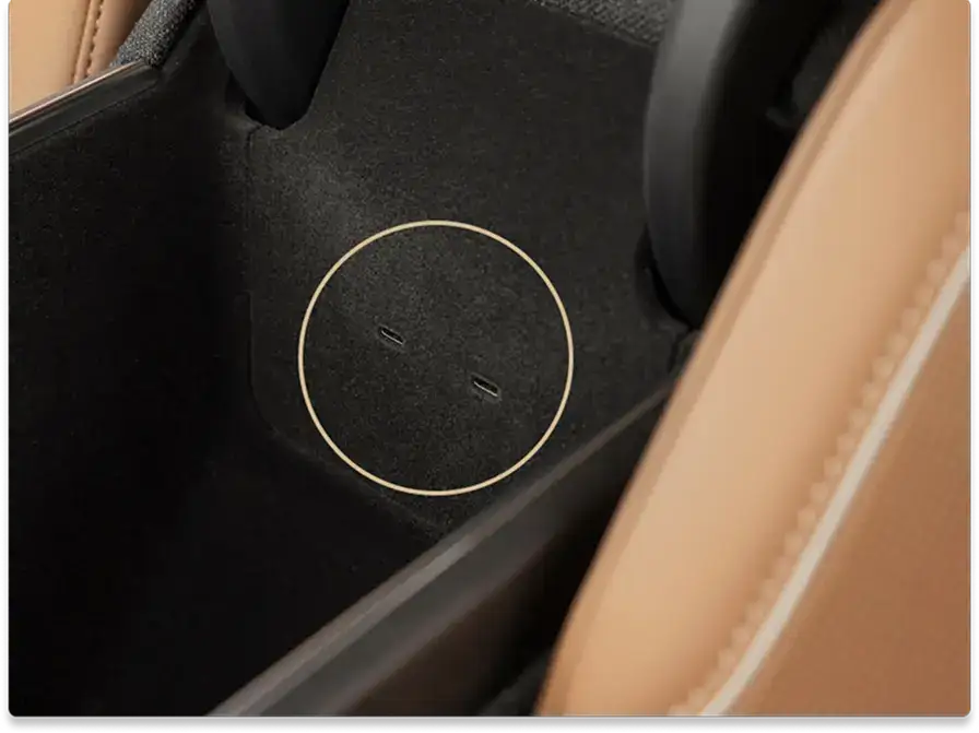 Close-up of a car interior storage compartment with black carpet lining and tan leather trim visible on the edges.