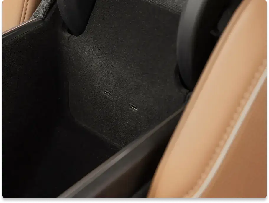 Close-up of a car interior showing a black carpeted floor area with tan leather trim along the edges.