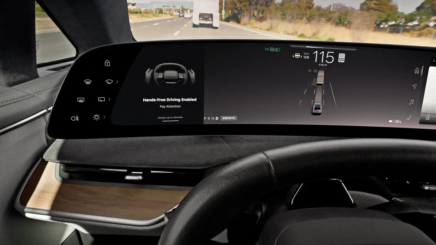 Car interior dashboard screen displaying "Hands-Free Driving Enabled" at 115 km/h on a highway.