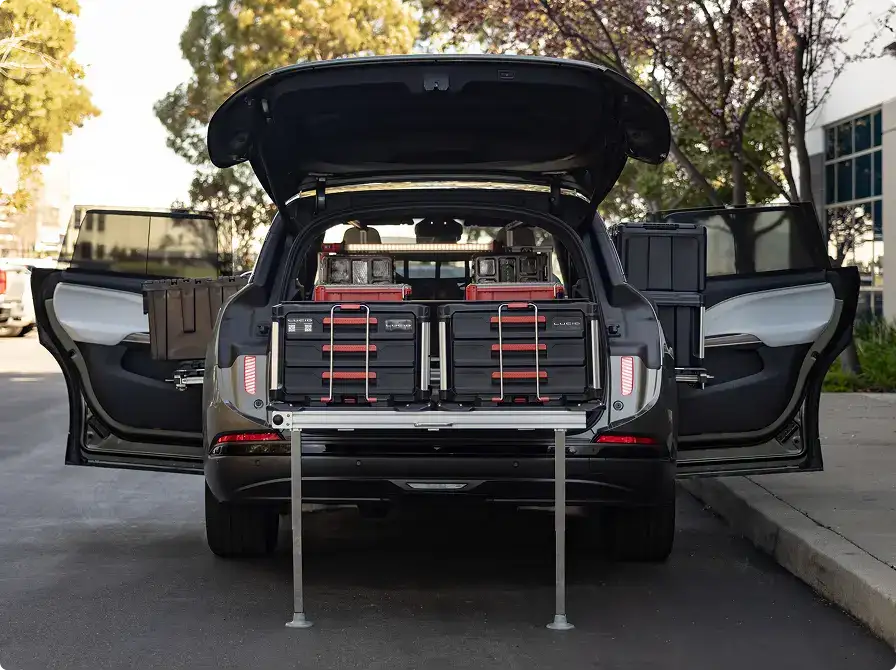 Lucid Gravity with open trunk and doors, loaded with black and red tool storage cases on a sliding cargo platform.