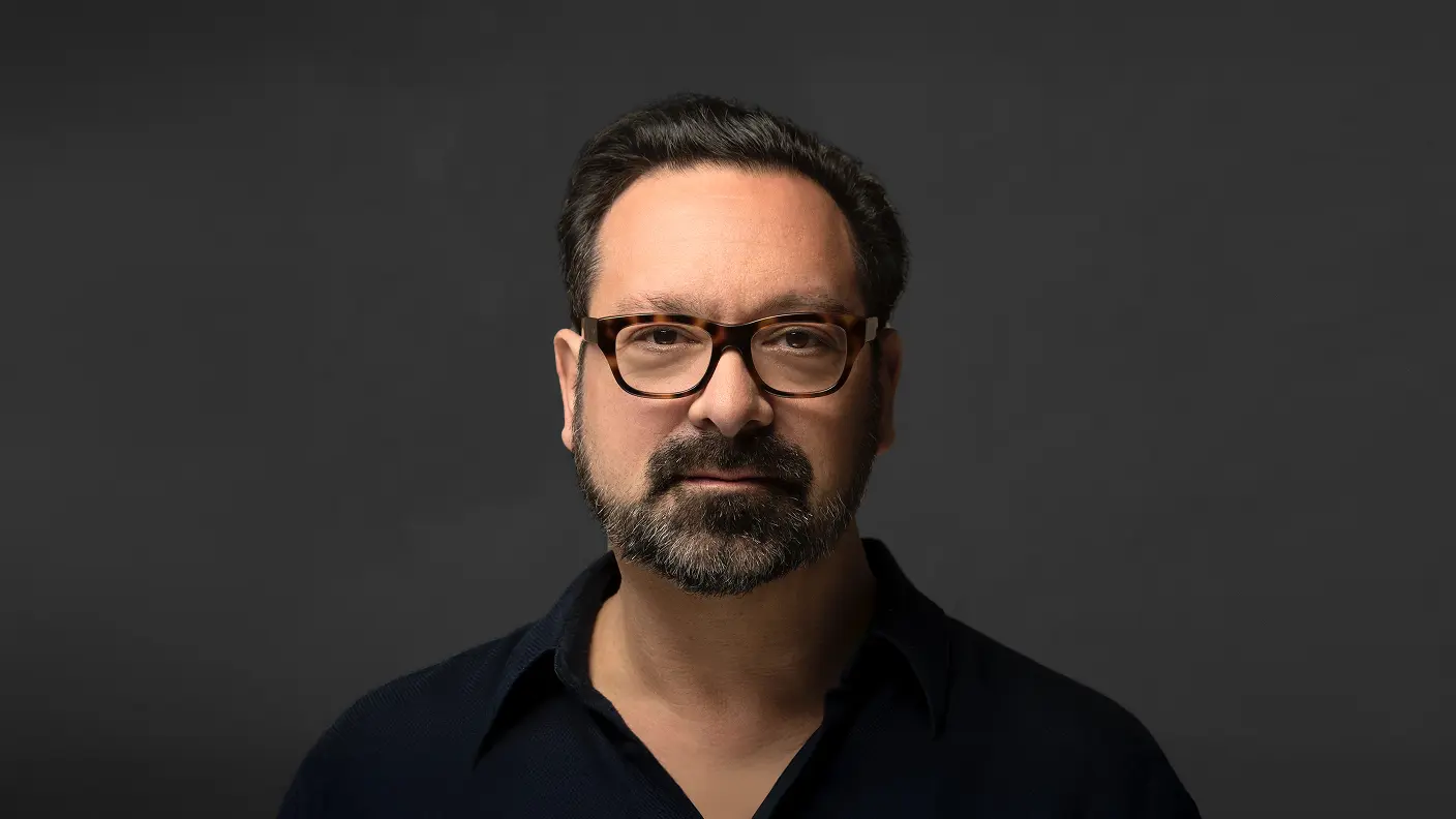 Professional portrait of James Mangold wearing a dark shirt against a gray background.