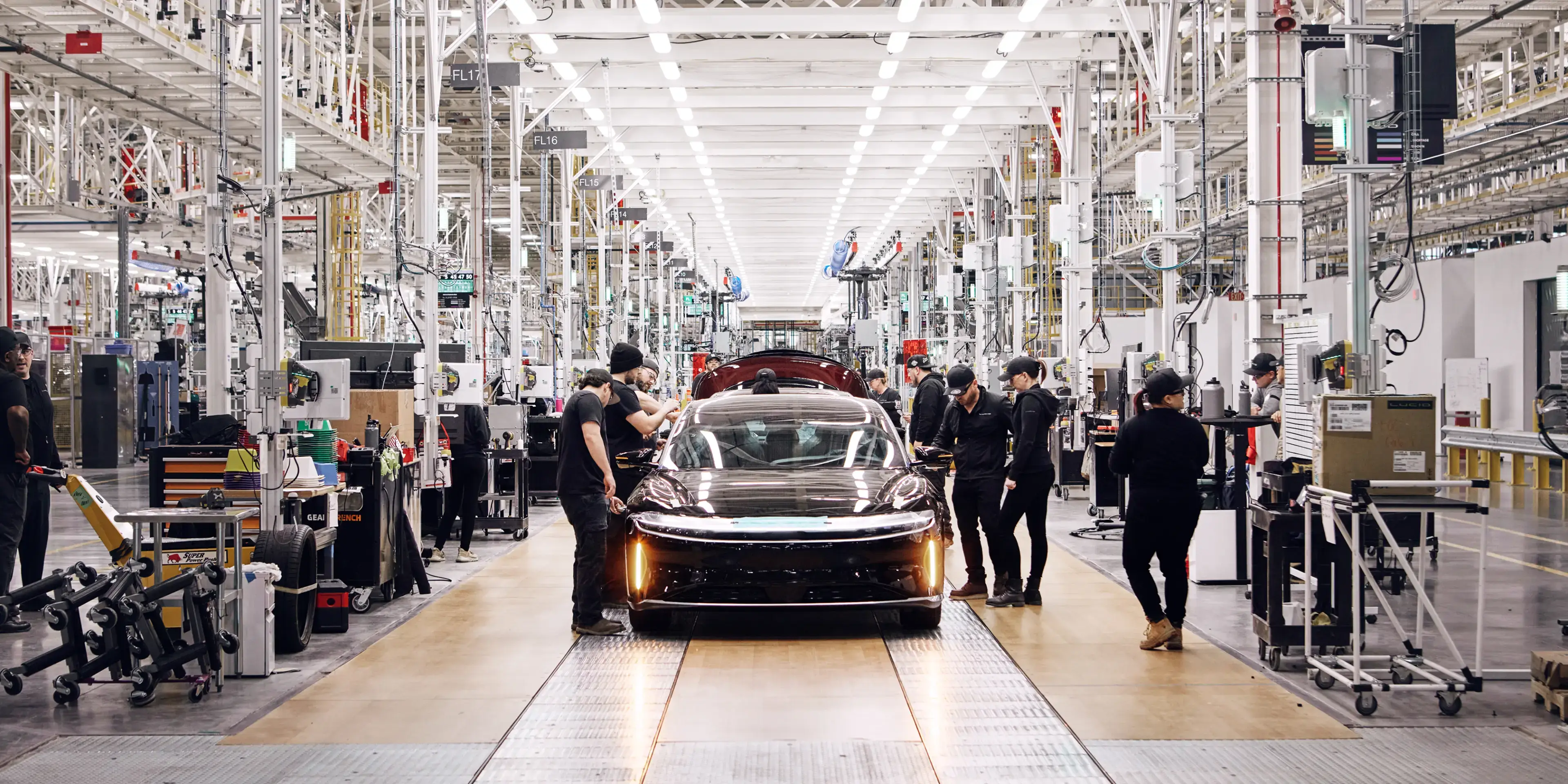 Modern car manufacturing facility with workers assembling sleek electric vehicles on a bright production line.