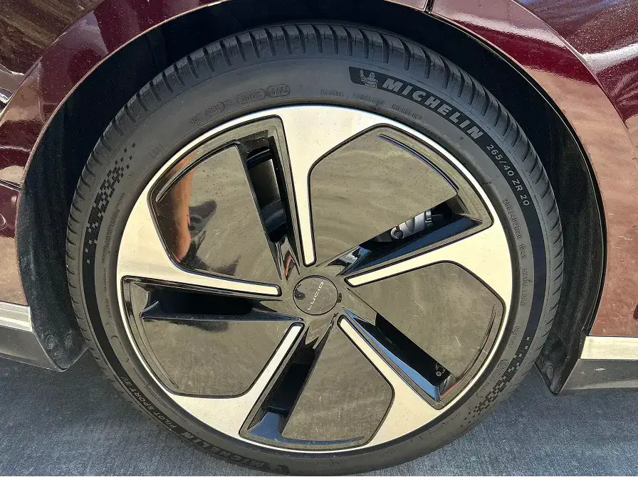 Close-up of a burgundy car's wheel featuring a modern five-spoke alloy rim and Michelin tire.