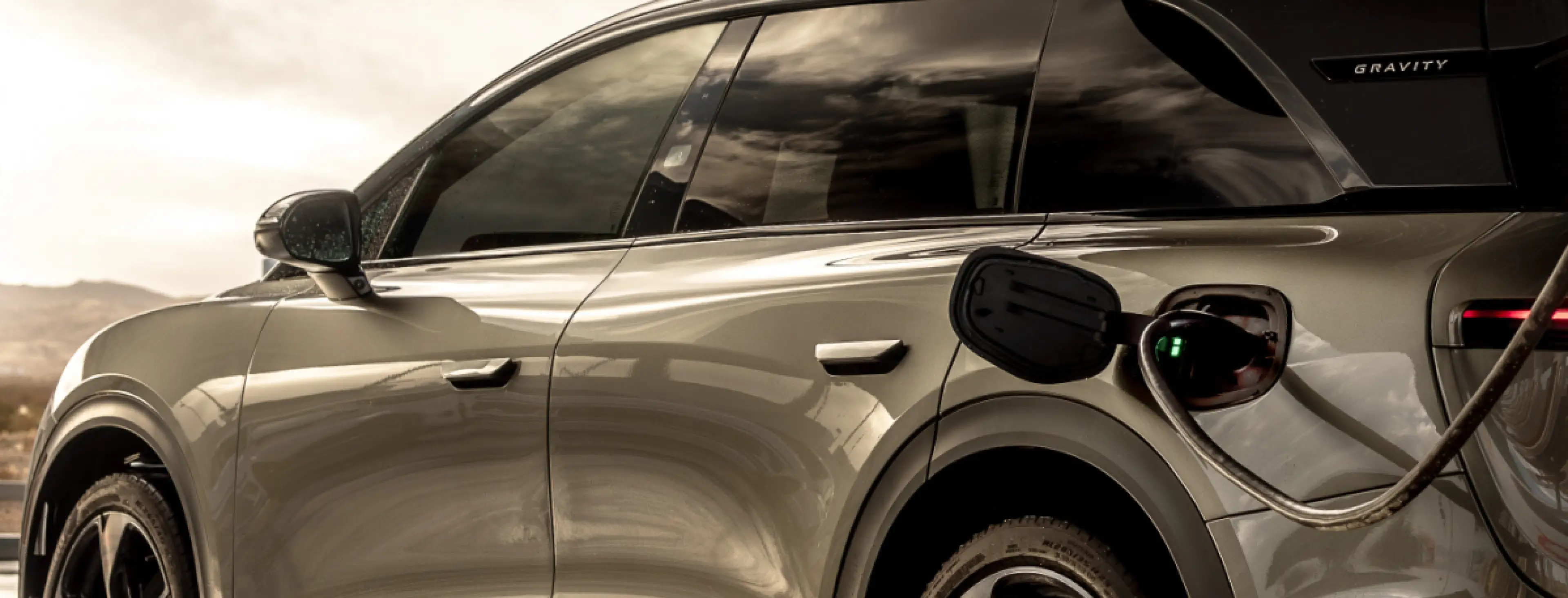 Lucid Gravity plugged in and charging, showing the vehicle's side profile and charging port.