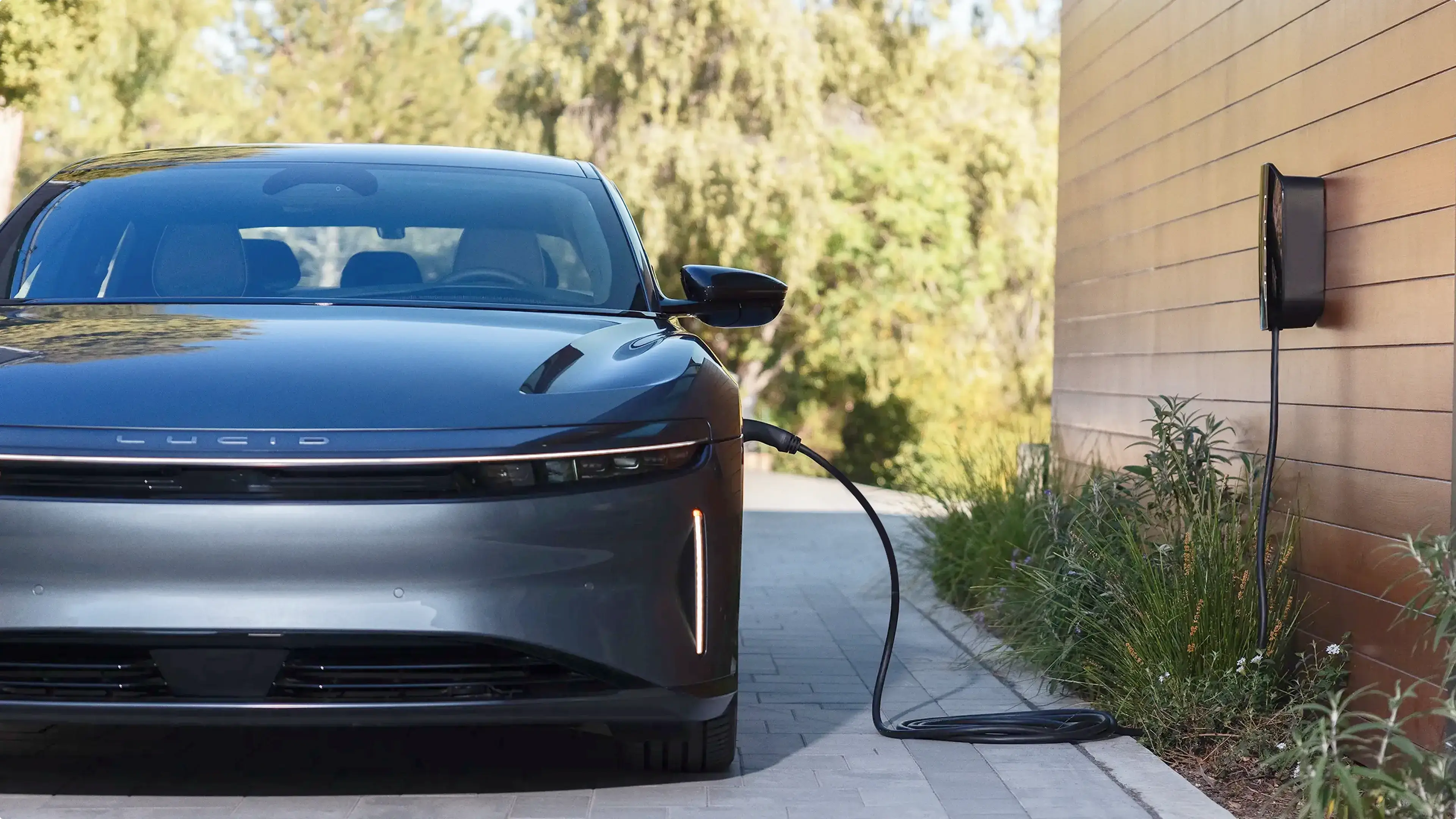 Sleek white electric car charging at a modern home with minimalist architecture and warm lighting at dusk.