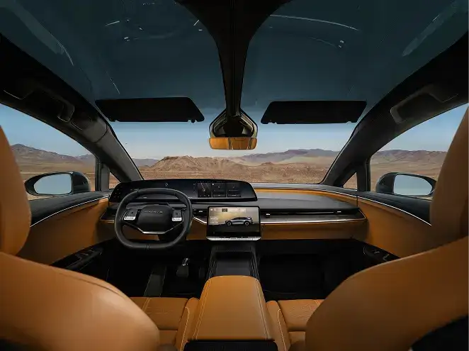 Modern car interior with tan leather seats, sleek dashboard, large touchscreen, and a panoramic view of desert mountains.