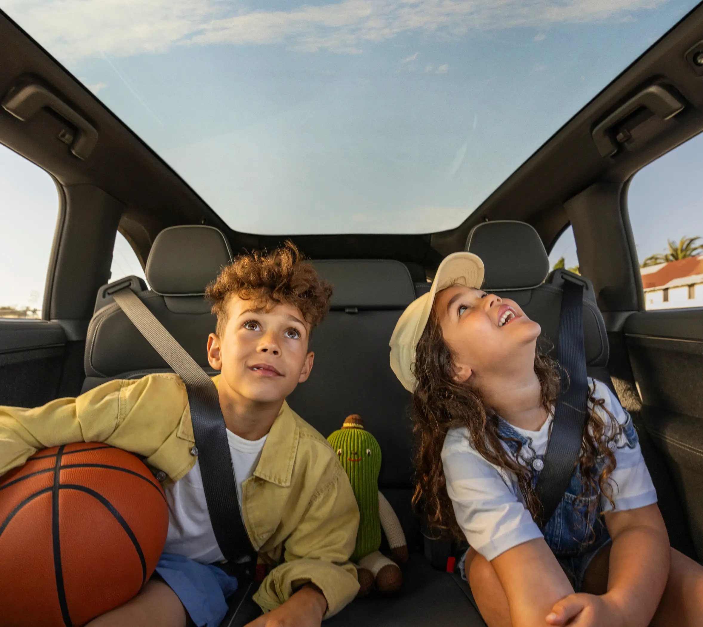 Zwei Personen interagieren im Innenraum einer Lucid Gravity mit umgeklappten Rücksitzen, während Basketbälle und eine Kühlbox im hinteren Bereich liegen.