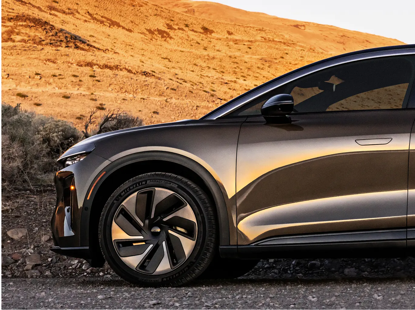 The modern wheel design of the sleek Lucid Gravity SUV at sunset.