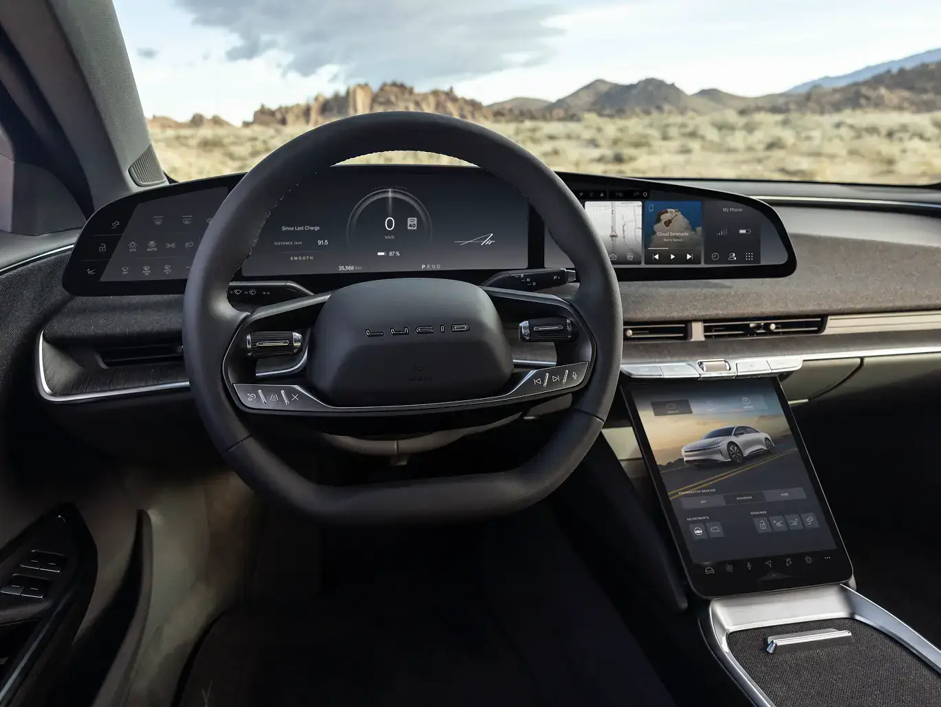 Modern car dashboard with digital displays and touchscreen interface, overlooking a desert landscape with mountains.