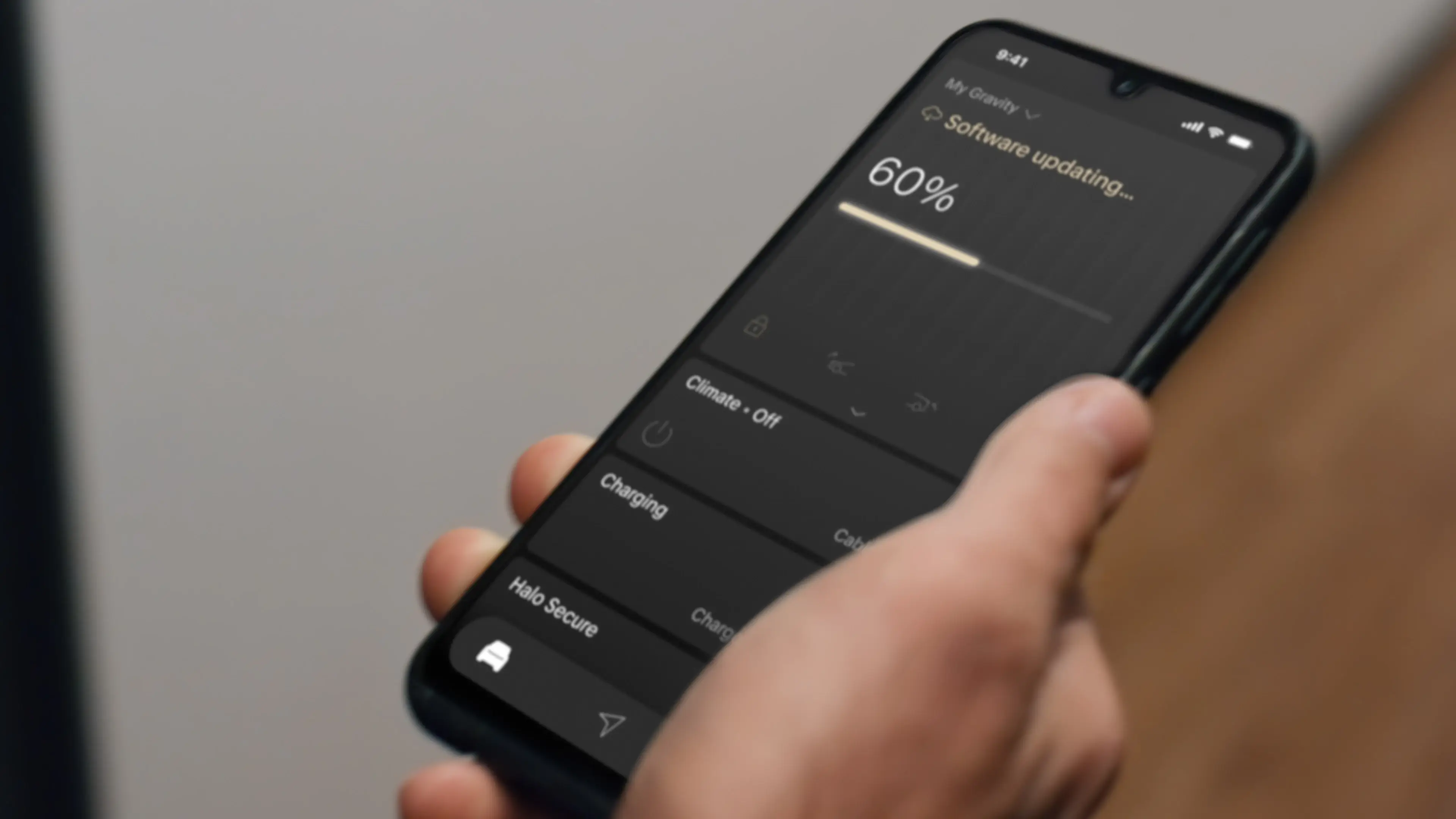 Hand holding smartphone displaying "Software updating" at 60% progress with vehicle controls visible in dark mode interface.