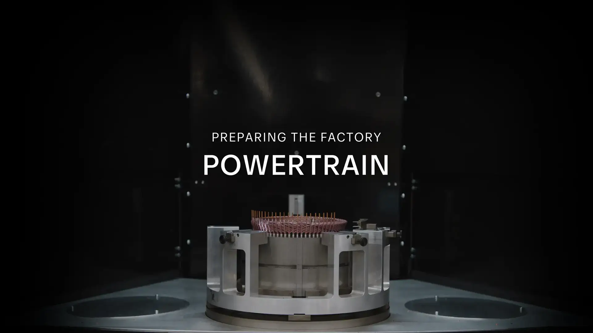 Industrial powertrain component with copper coils on display against dark background, text reads "PREPARING THE FACTORY POWERTRAIN"
