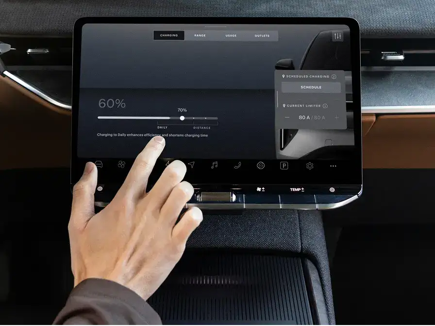 A hand touching an electric vehicle's touchscreen displaying a charging menu showing 60% battery level.