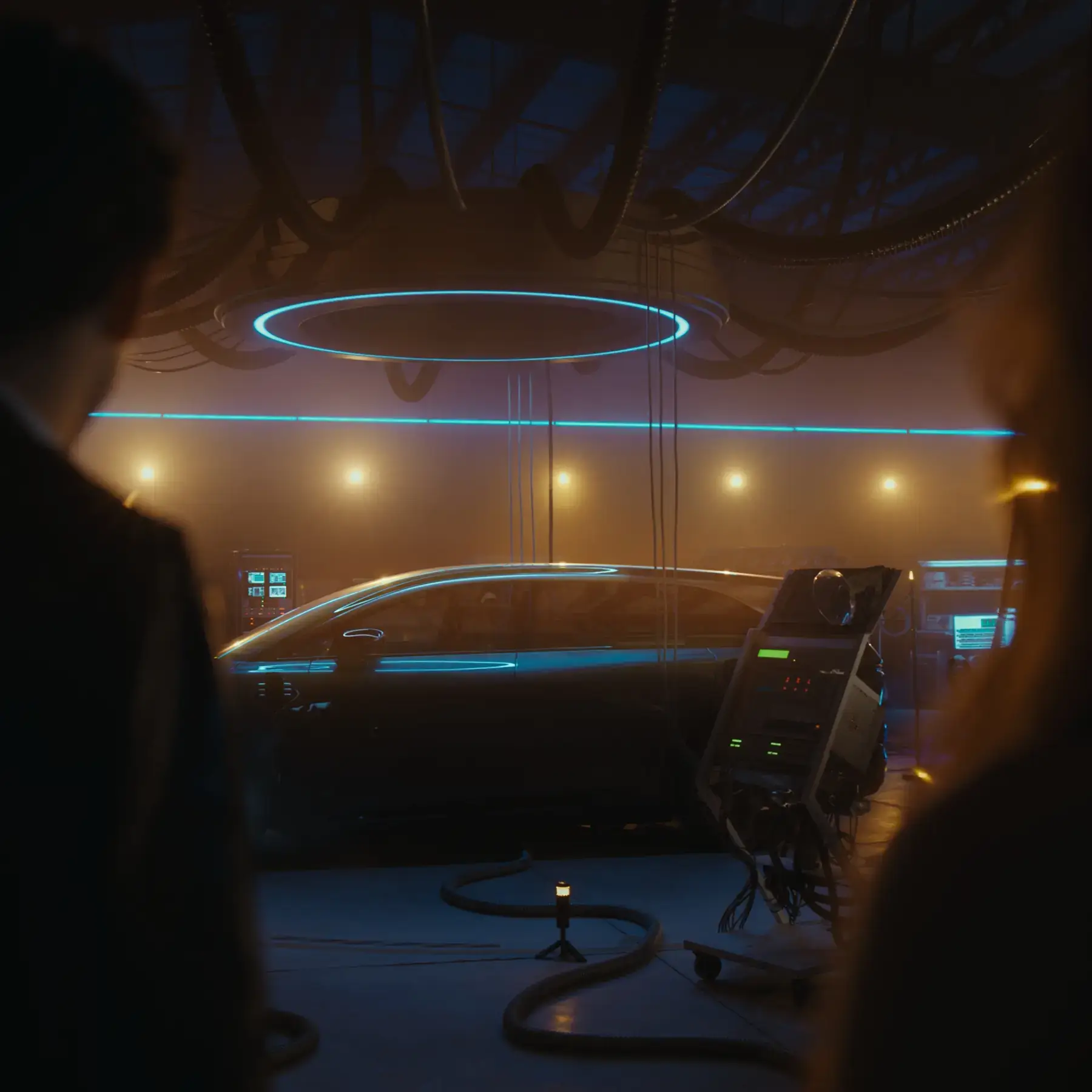 Futuristic car in a dimly lit garage with blue neon lighting and control panels, creating a high-tech atmosphere.