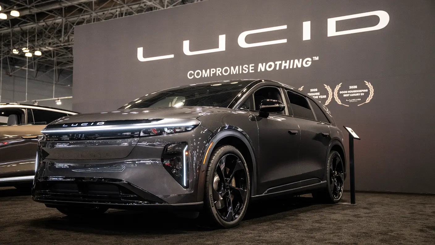 Lucid Gzravity SUV displayed at auto show with "COMPROMISE NOTHING" slogan and award emblems on backdrop.