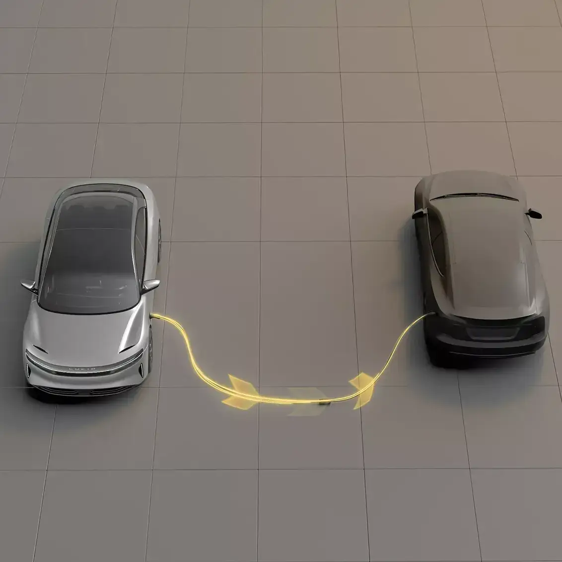 Aerial view of silver and black electric vehicles connected by a glowing yellow charging cable on a gray tiled floor.