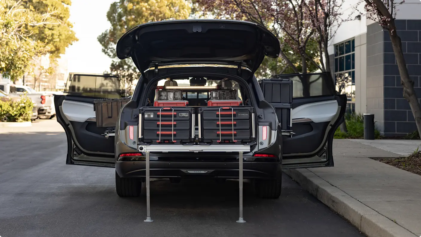 Lucid Gravity SUV with open trunk and doors displaying organized storage system with tool cases and pull-out rack.