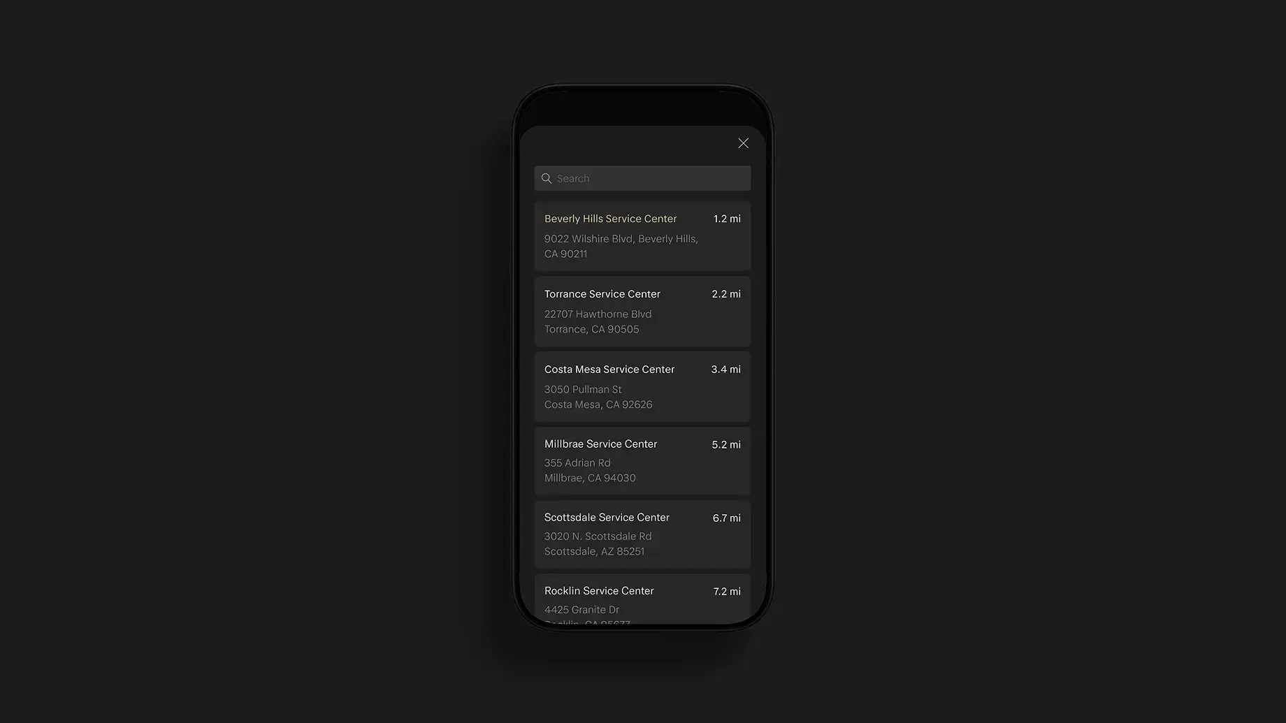Smartphone displaying a dark-themed app screen listing nearby service centers with addresses and distances in miles.