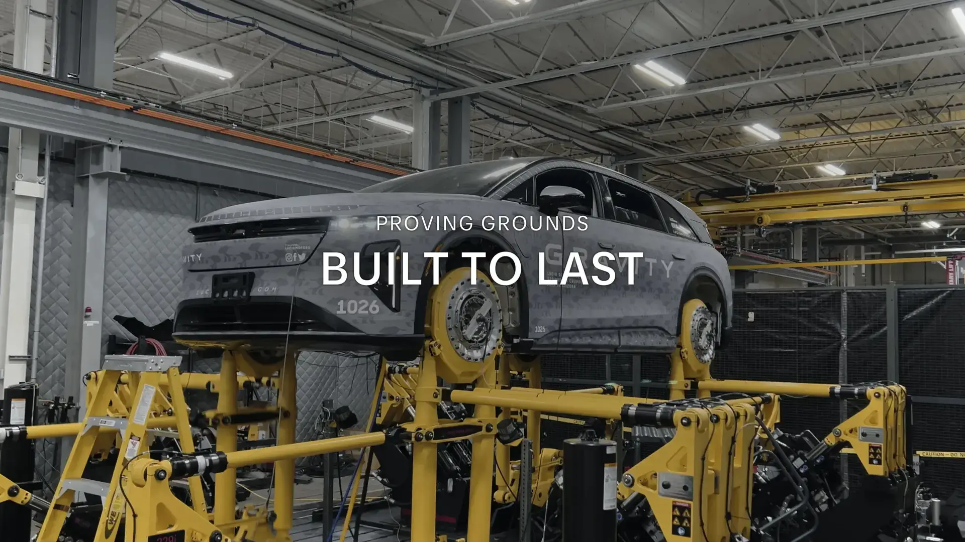 SUV on yellow testing equipment in factory with text overlay "PROVING GROUNDS BUILT TO LAST"