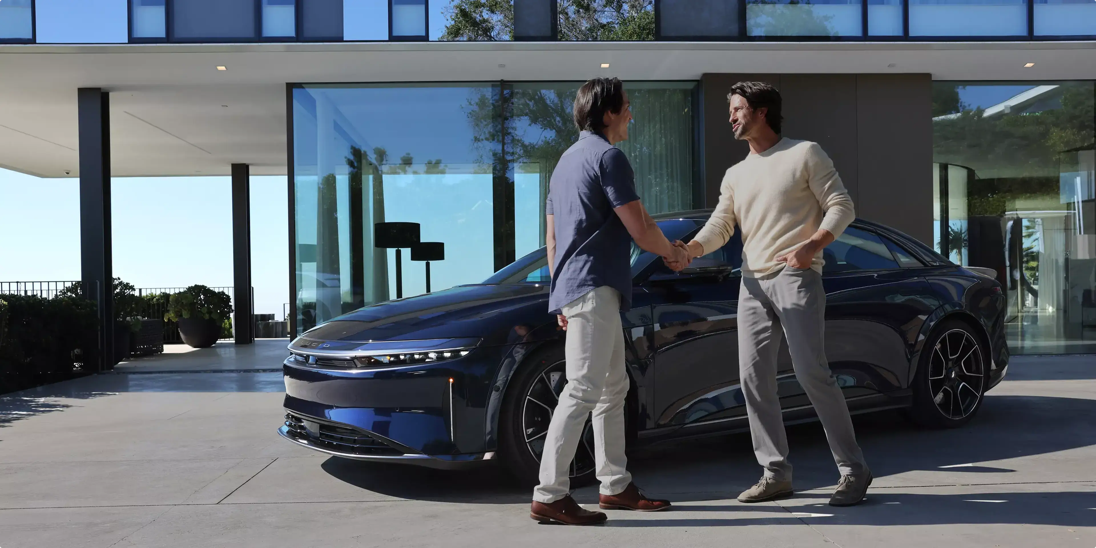 Image of two men shaking hands in front of a Lucid Air Sapphire