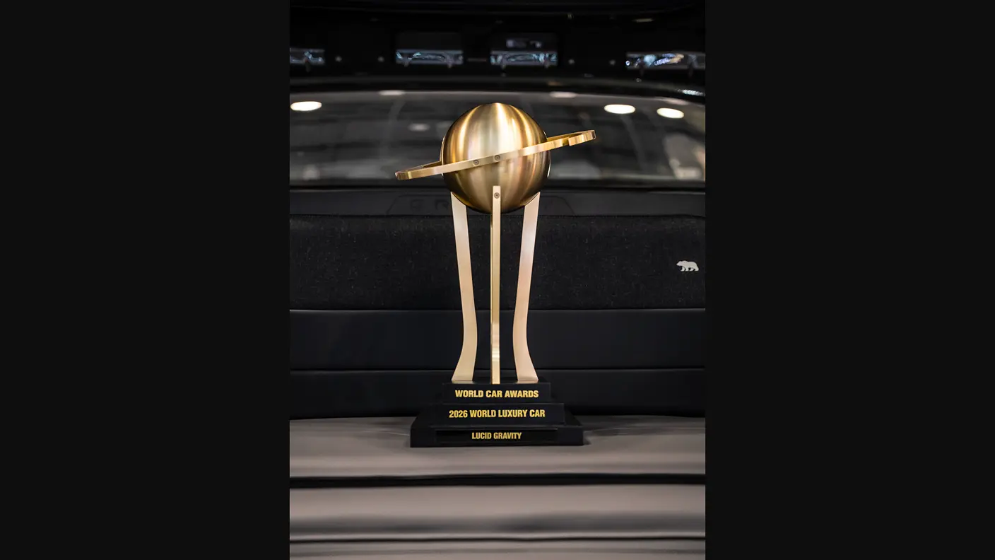 Gold trophy for 2025 World Luxury Car awarded to Lucid Gravity, displayed on a black car hood with bear emblem.