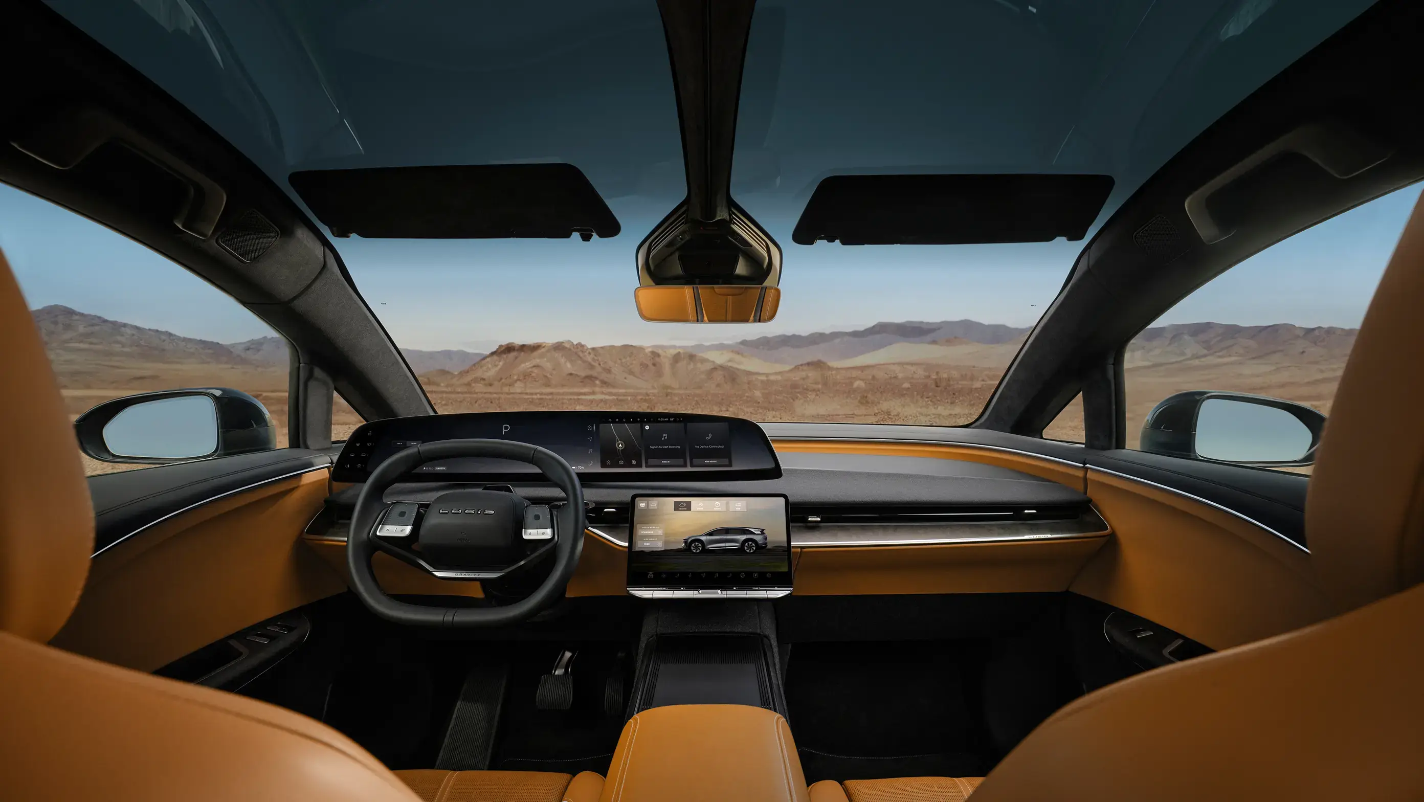 View from inside a luxury car with orange leather interior, digital displays, and panoramic sunroof overlooking desert mountains.