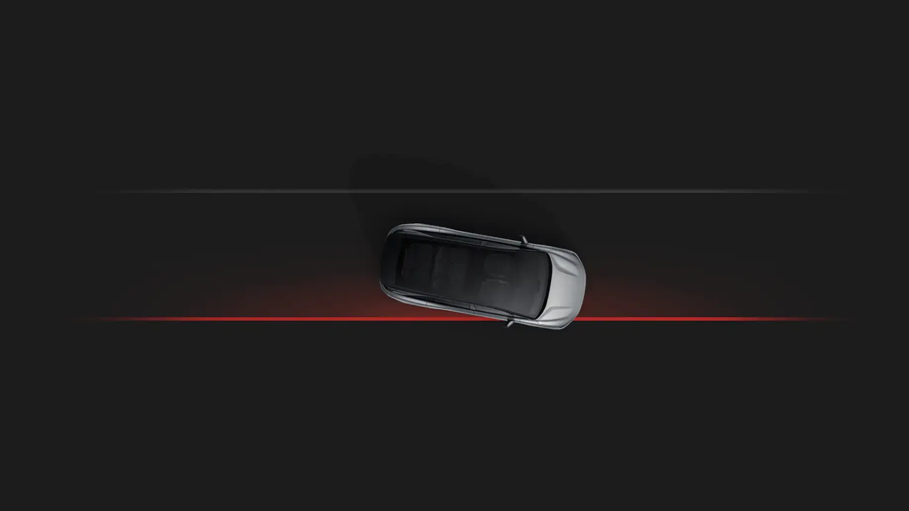 Aerial view of a silver SUV on a dark road with a red line beneath, illustrating lane-keeping or safety technology.