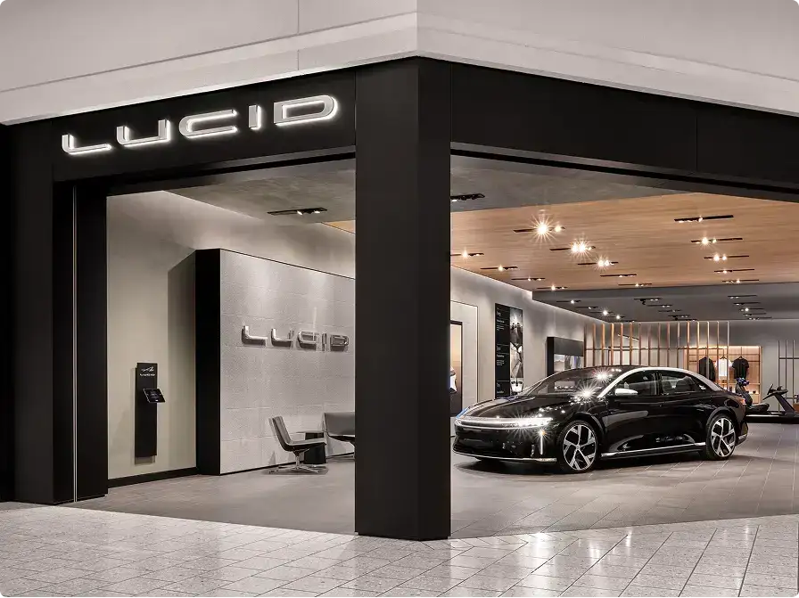 A sleek black Lucid electric sedan displayed inside a modern Lucid Motors showroom with illuminated signage.