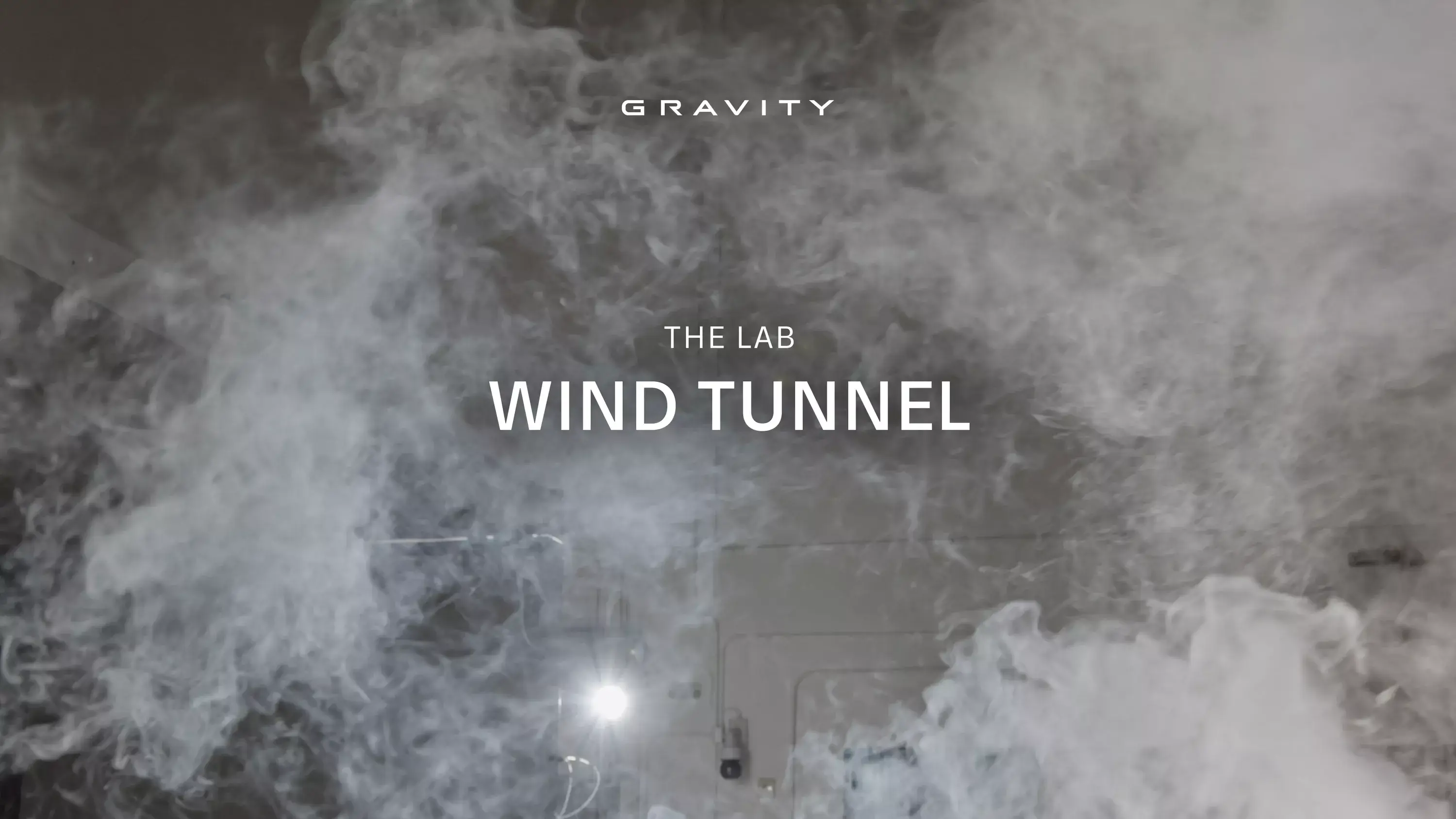Gravity wind tunnel lab with swirling smoke patterns against a gray background, featuring bold white text overlay.