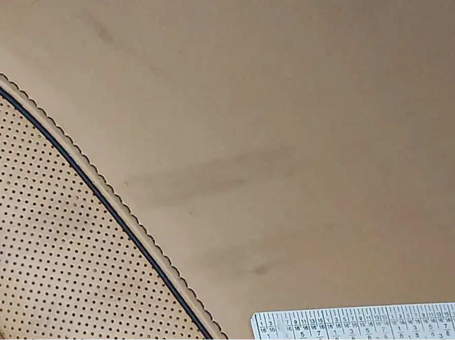 Close-up of beige perforated fabric with scalloped edge trim, with a clear ruler visible in the bottom right corner.