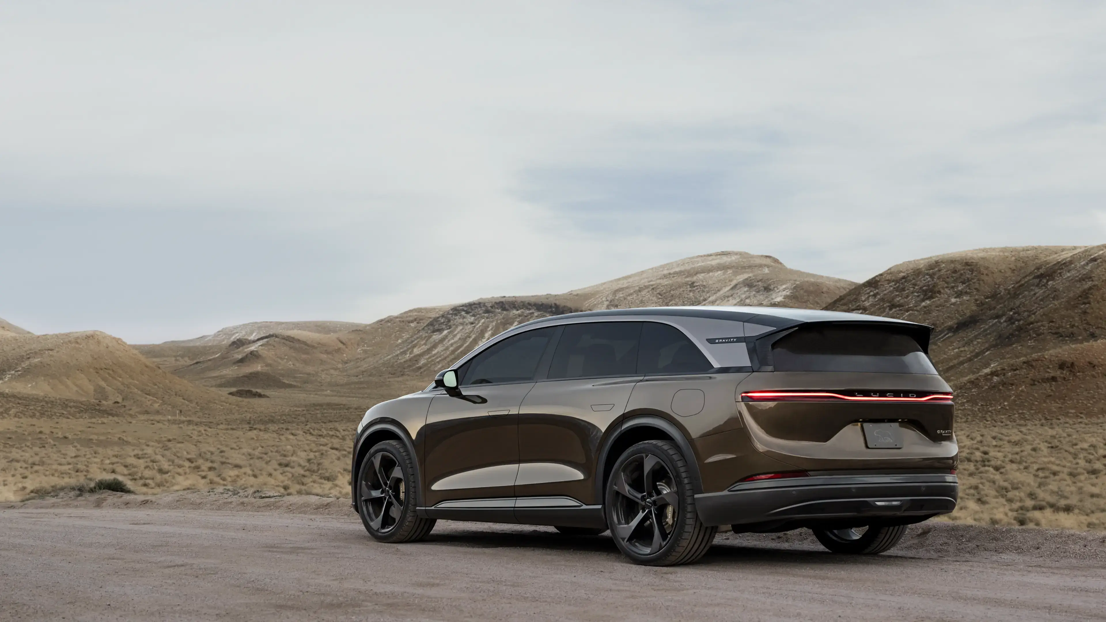 La Lucid Gravity stationnée dans un paysage désertique avec des collines brunes et un ciel couvert en arrière-plan.