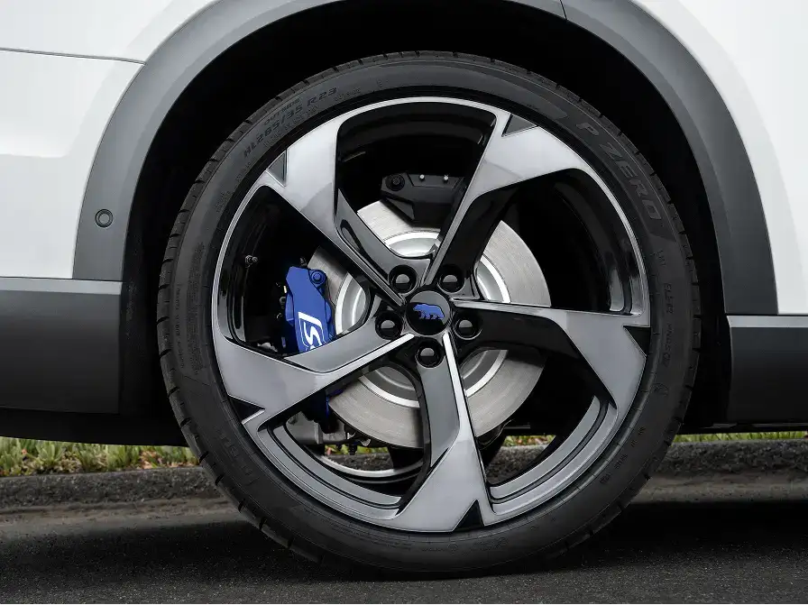 Close-up of a white SUV's dark alloy wheel with a Pirelli P Zero tire and a blue brake caliper.