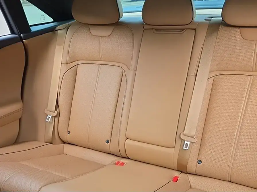 Luxury car interior with tan leather rear seats, seatbelts, and headrests visible in a clean, modern cabin.