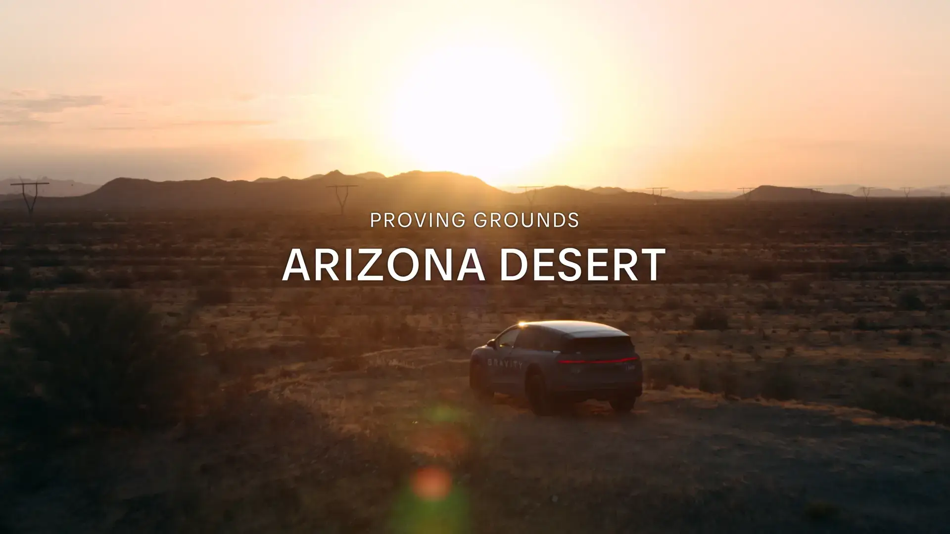 Car driving through Arizona desert at sunset with mountains in background and "PROVING GROUNDS ARIZONA DESERT" text overlay.