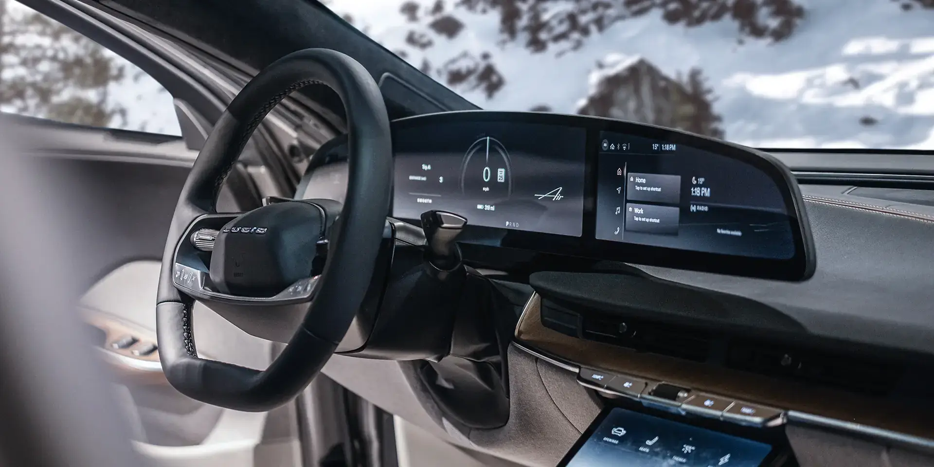 Lucid Air interior with digital dashboard displays and touchscreen controls, snowy mountains visible through windshield.
