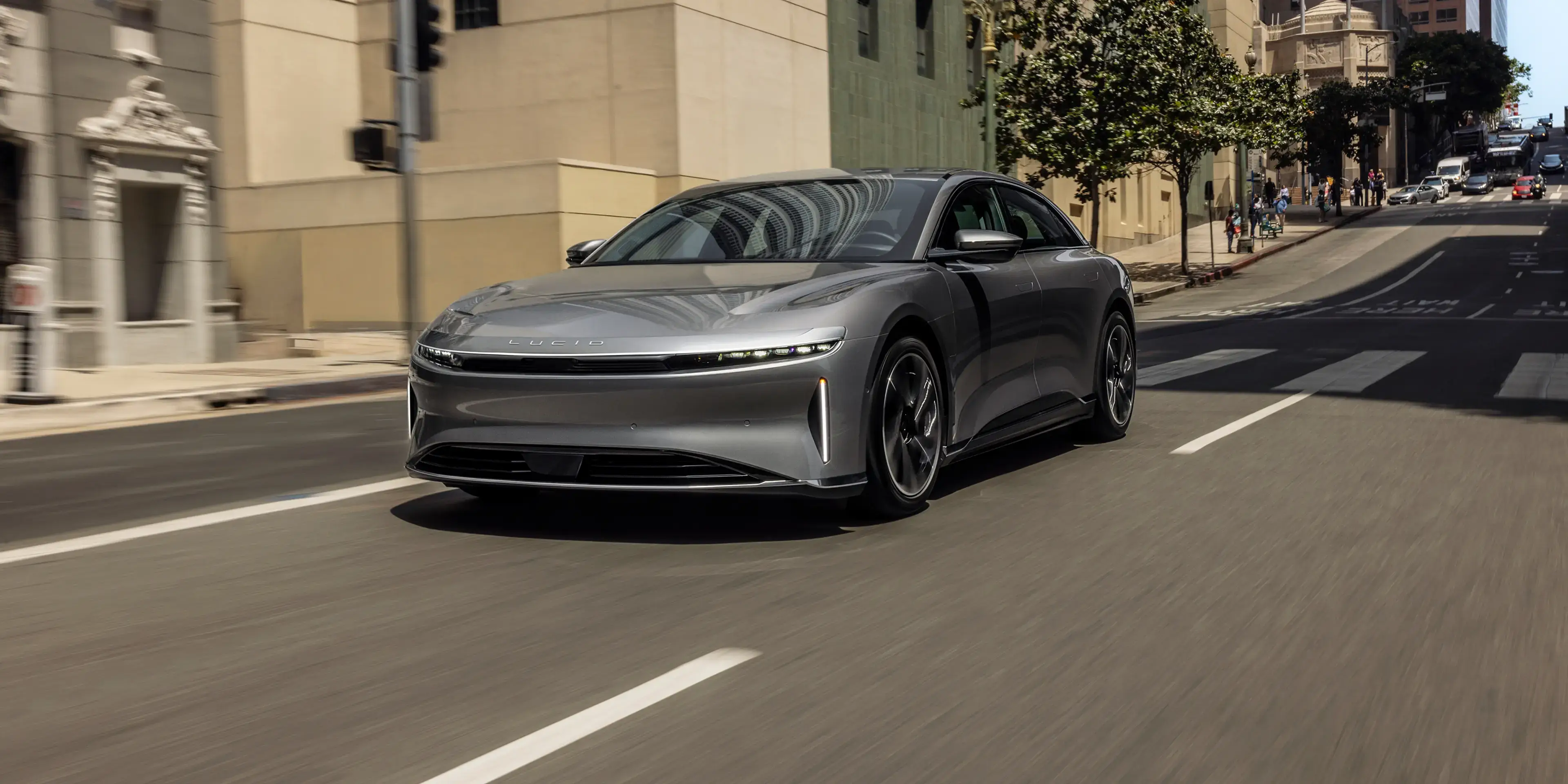 Lucid Air stationnée sur un terrain désertique, avec des montagnes enneigées en arrière-plan.