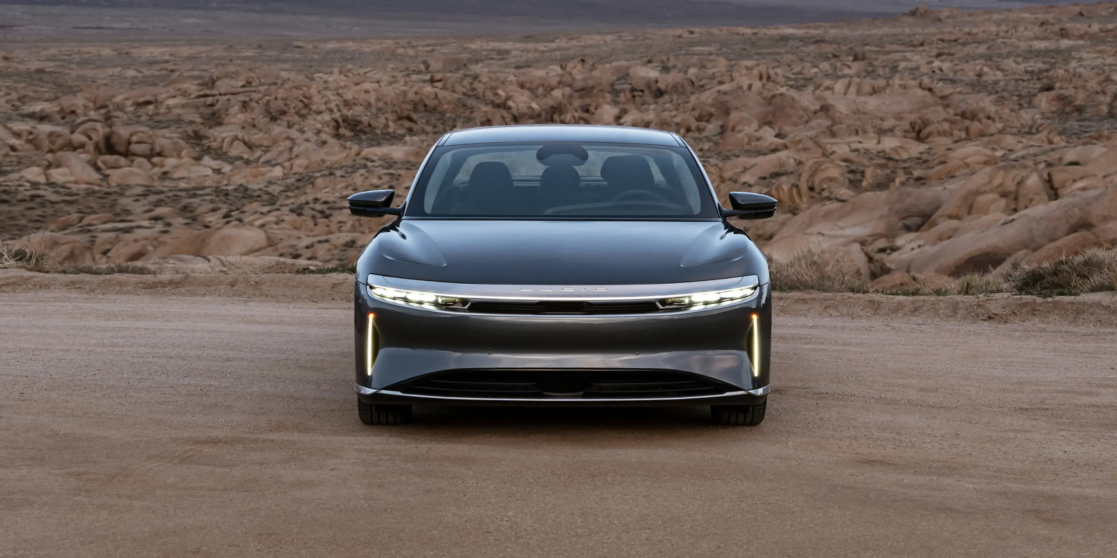 Lucid Air stationnée sur un terrain désertique avec des montagnes enneigées en arrière-plan.