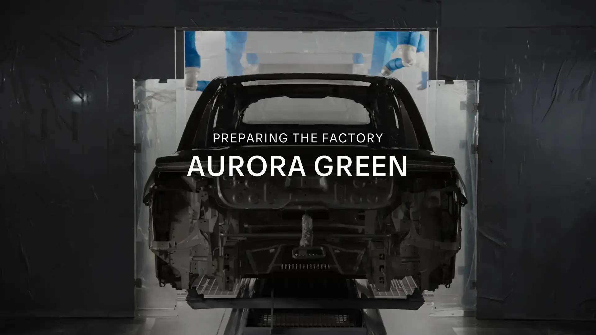 Car frame in factory assembly line with text overlay "PREPARING THE FACTORY AURORA GREEN"