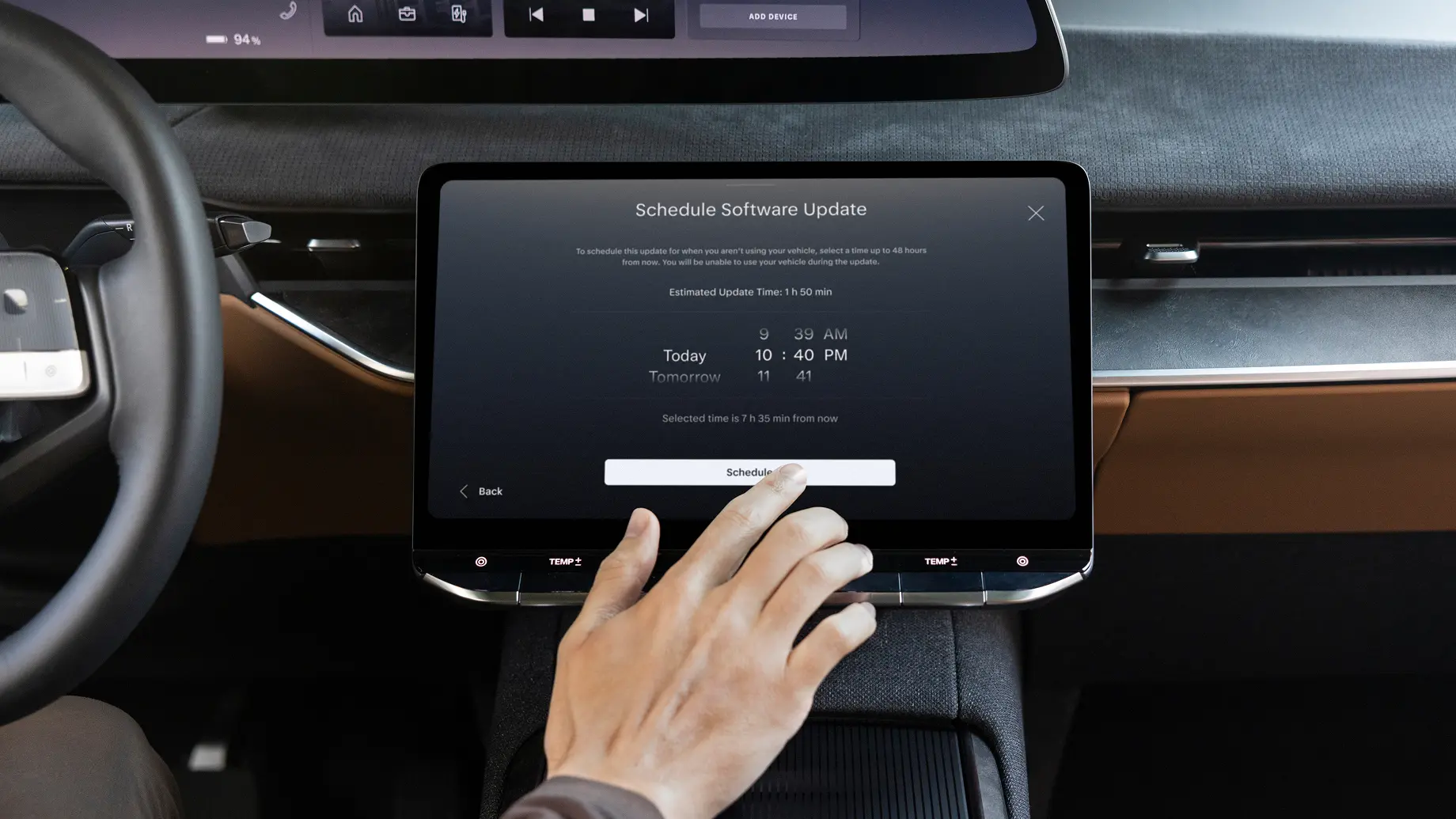 A hand tapping a car touchscreen displaying a "Schedule Software Update" dialog with time selection options.