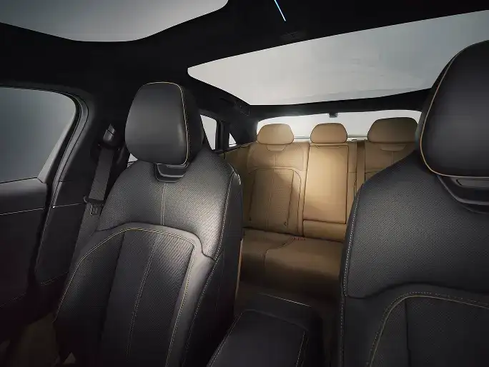 L’intérieur d’une Lucid Air avec des sièges avant en cuir noir, des sièges arrière beiges et un toit panoramique en verre laissant entrer la lumière naturelle.