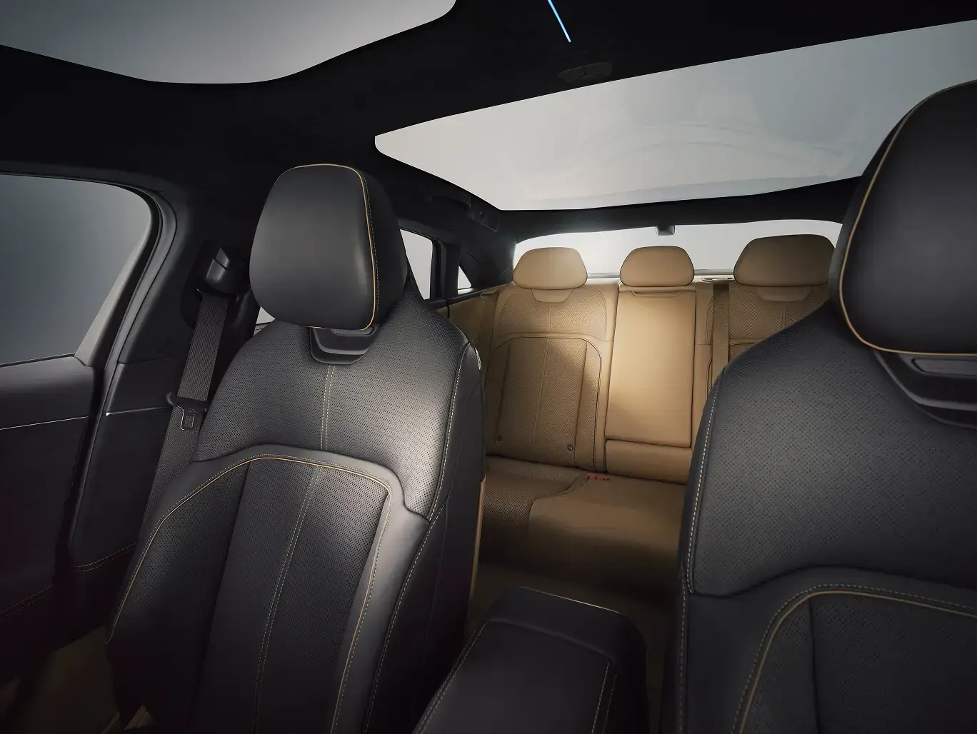 Lucid Air interior with black leather front seats, tan rear seats, and panoramic glass roof letting in natural light.