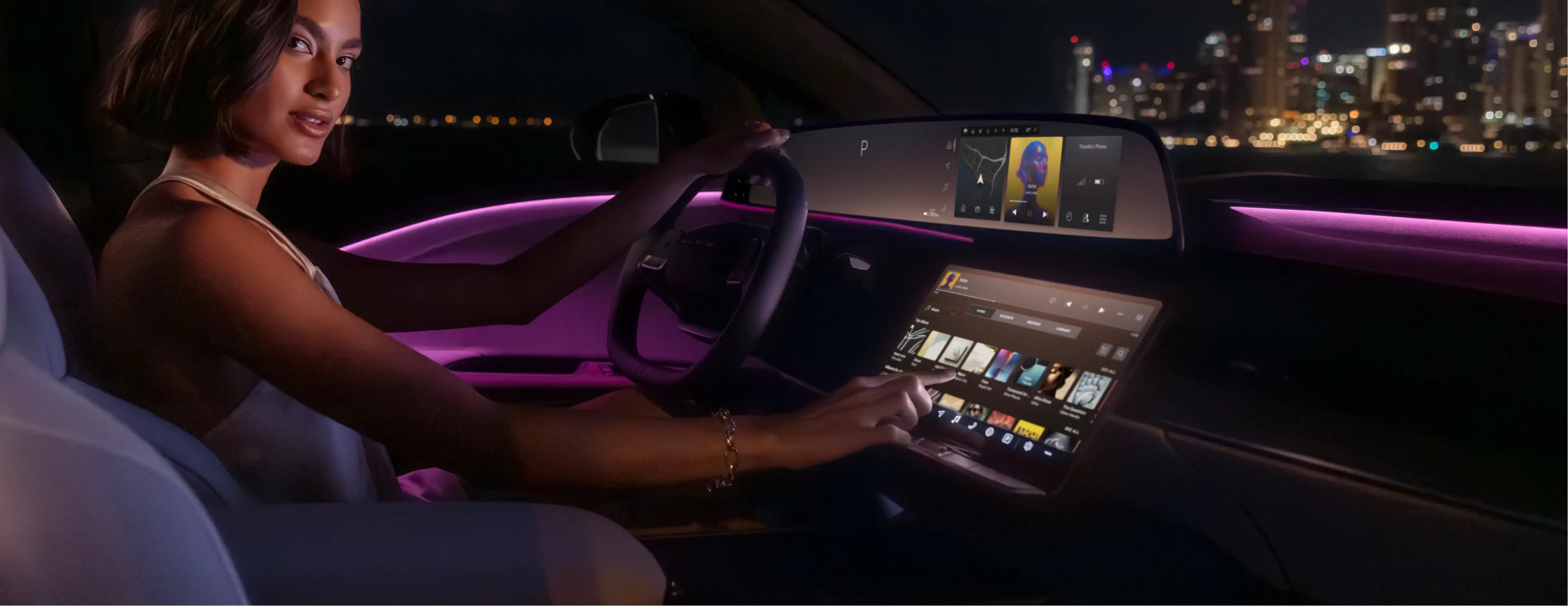 Woman sitting in a modern car at night, touching a large touchscreen dashboard with pink ambient interior lighting.