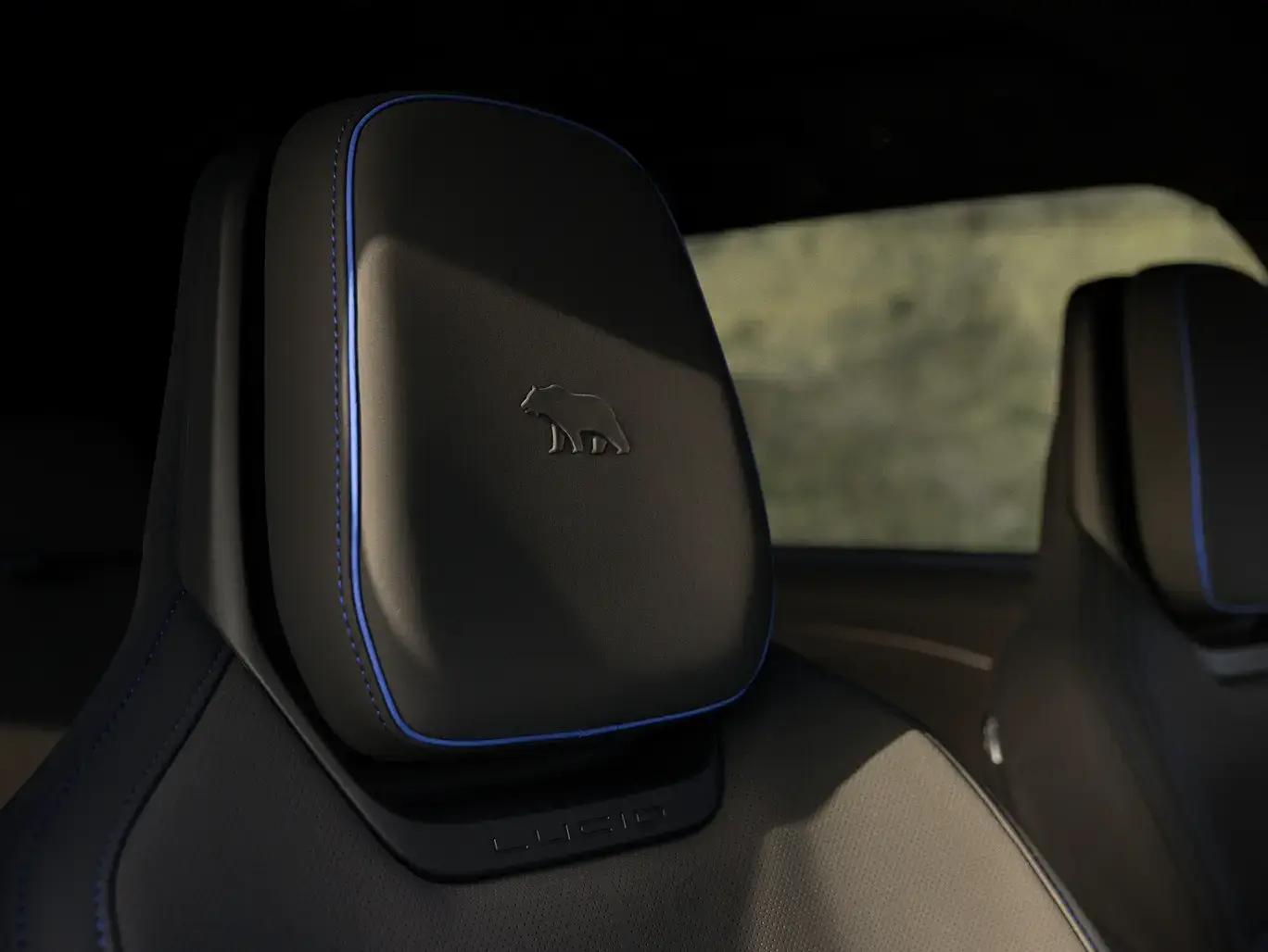 Black leather car headrest with blue piping, embossed bear logo, and "Lucid" branding on the seat back.